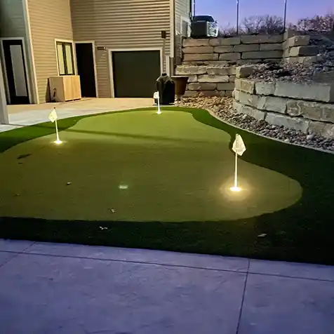 An artificial turf putting green lit up at night