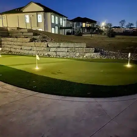 An artificial turf putting green lit up at night