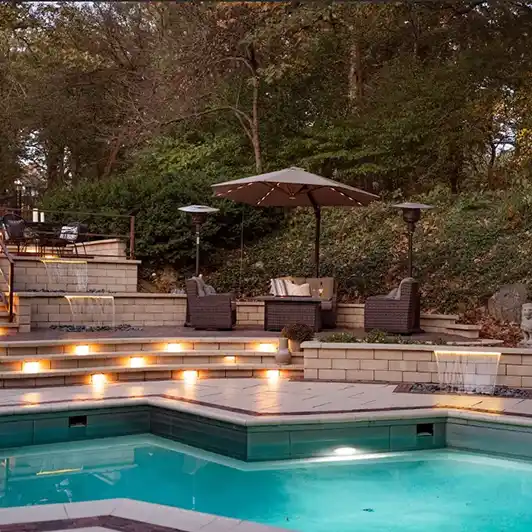 A multi-level outdoor living space with a stone staircase, seating areas, a pool, and fountains