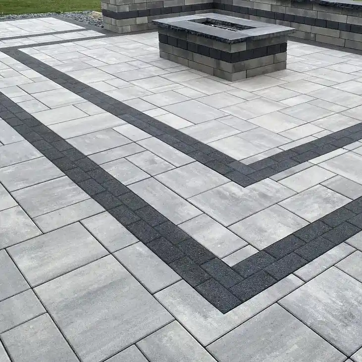 A patterned stone-paved patio area with a fireplace and a stone wall