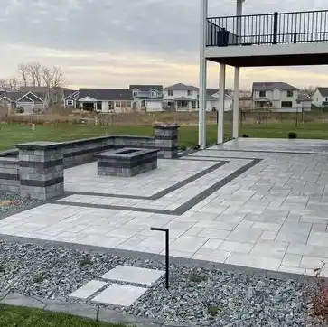 A patterned stone-paved patio area with a fireplace and a stone wall