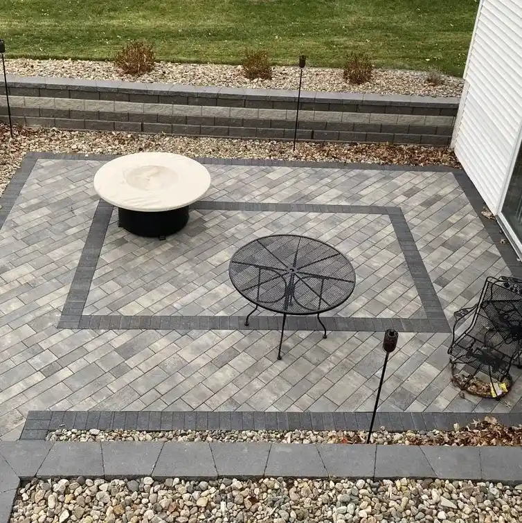 A patterned stone-paved patio area surrounded by stone walls that contain garden beds