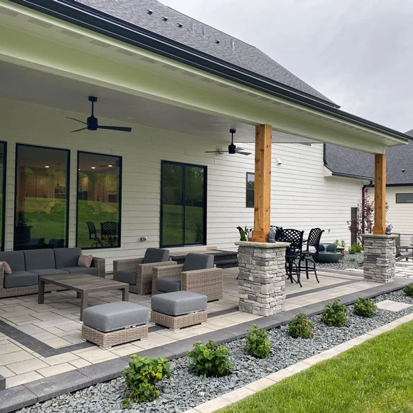 A covered stone patio area behind a home