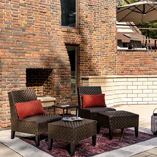 An outdoor patio area with a fireplace and two chairs 