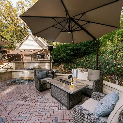A multi-level outdoor living space with shaded seating areas and a table with a fireplace in the middle