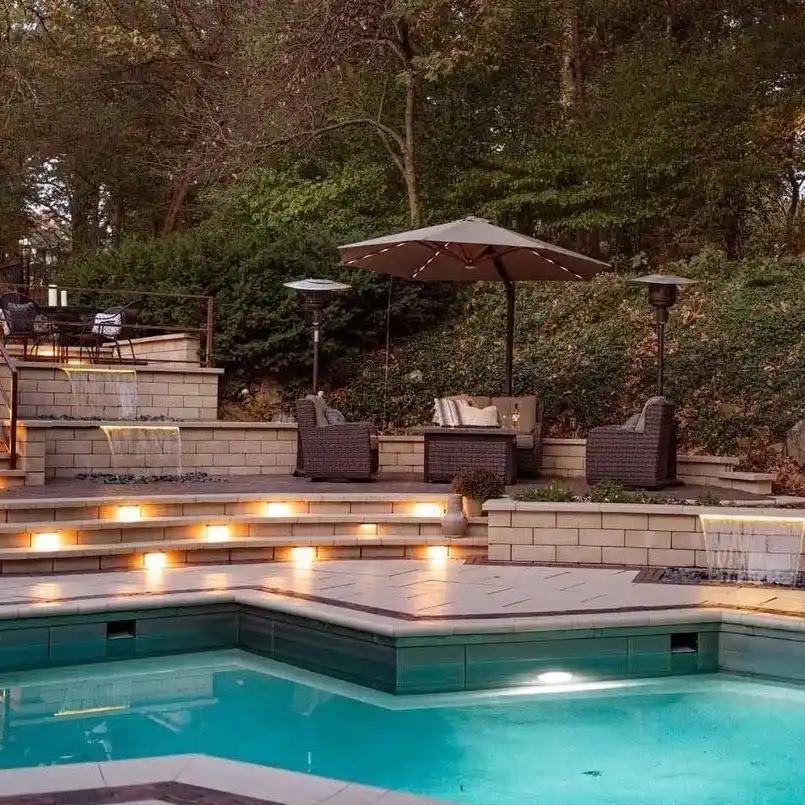 An outdoor pool sits next to an outdoor living space with shaded seating and fountains