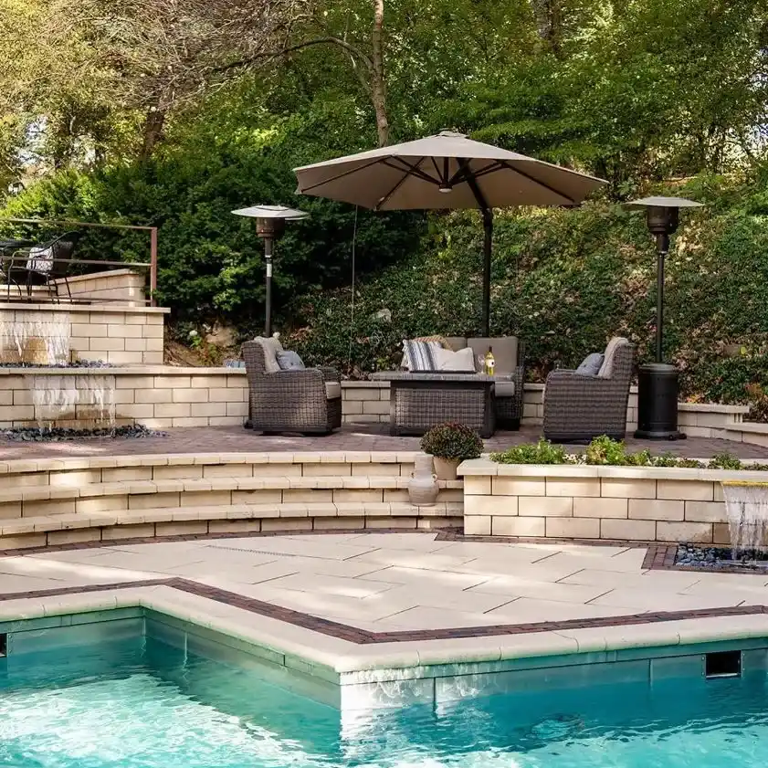 An outdoor pool sits next to an outdoor living space with shaded seating and fountains
