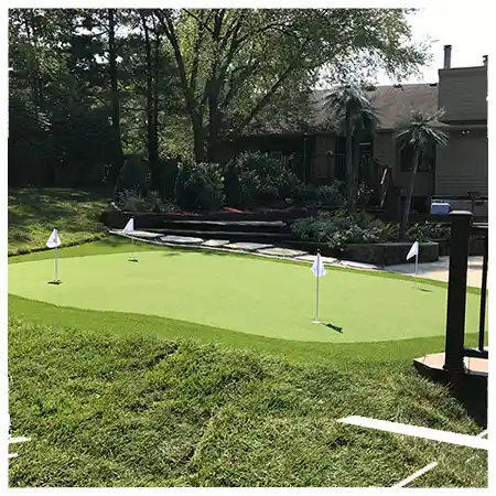 A turf putting green sits next to a stone walkway