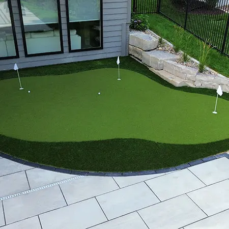An outdoor putting green built beside a house